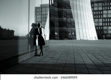 Black And White Photo Of A Girl In A Coat Reflecting In The Building Against The Business Center