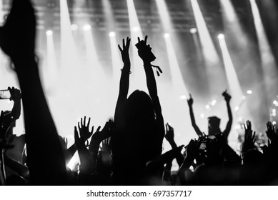 Black and white photo of a girl raising hands while enjoying good music.