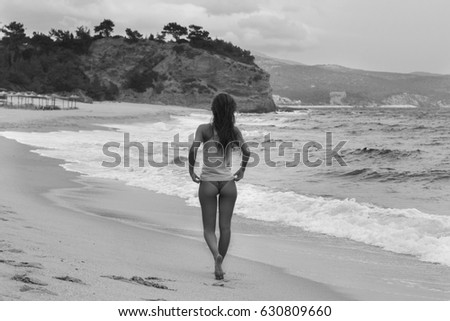 Black and white photo of handsome girl walking on the sand beach