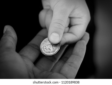 Black And White Photo Of Kid Giving One Pound Coin To Homeless,Crop View Of Children Hand Giving Money Coin To Another Person,Children Learning About Sharing And Giving And Donation Concept