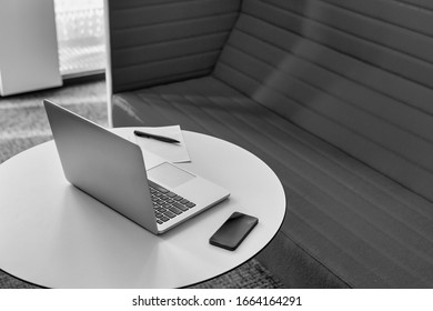 Black and white photo of laptop and smartphone on table in office