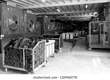 Black And White Photo Of The Laundry Workshop With Old Washing Machines And Baskets Full Of Jeans