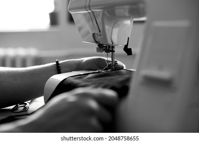 Black and white photo of Man sews clothes on sewing machine,  male tailor working with sewing in atelier, textile industry, hobby, workspace, small busines. Creation process DIY - Shutterstock ID 2048758655