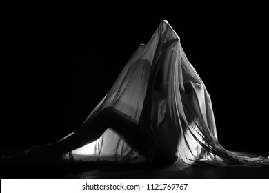 Black and White photo in Nude Artistic sensual sexy look of beautiful figure girl under hiding in light thin fabric, to show silhouette of woman body lying on floor, up waist chest female in shadow