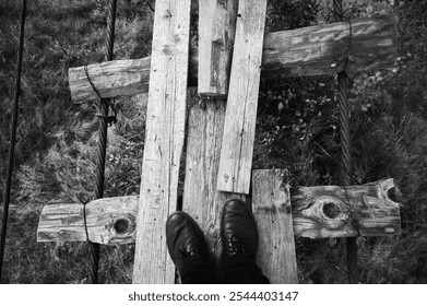 black and white photo, an old broken suspension bridge stretches across a river, creating a sense of adventure and danger. The worn wooden planks add an atmosphere of risk and picturesque rural landsc - Powered by Shutterstock