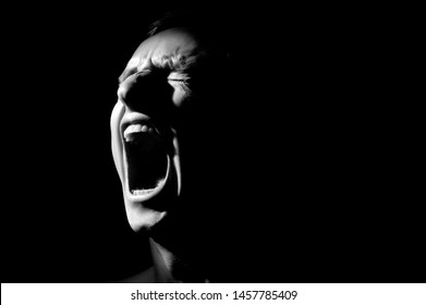 black and white photo on a black background, distorted face screaming - Shutterstock ID 1457785409