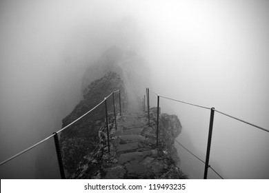 Black and white photo of the path to the Pico Ruivo and Pico do Arieiro mountain peaks in a fog in Madeira, Portugal. A mystic path, road to nowhere - Powered by Shutterstock
