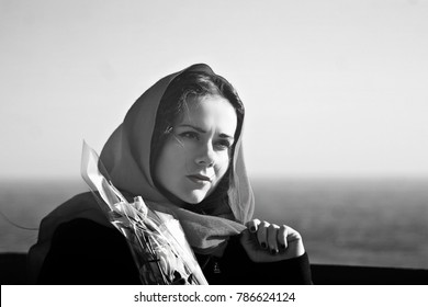 Black - white photo of a pensive girl in a red shawl with flowers on the background of the sea - Powered by Shutterstock