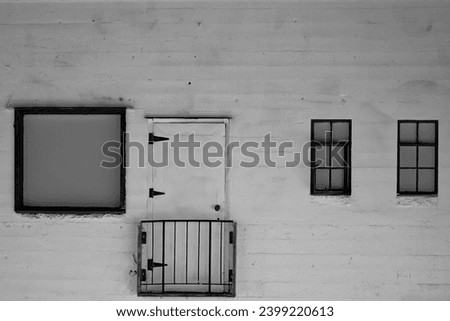 Black and white photo of a rundown brick building with an unusable door. 