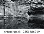 Black and white photo of a sandstone cliff reflected in a pool along Oak Creek, in the Coconino National Forest near Sedona, Arizona.