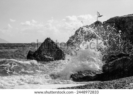 Black and white photo of the sea with rocks and sea splashes on the rocks in the summer, warm time.