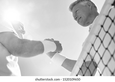 Black And White Photo Of Senior Tennis Athletes Shaking Hands In Court