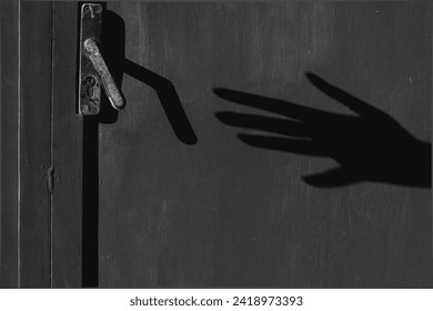 Black and white photo of a shadow of an arm with a hand trying to open a closed door. theft concept. fear. phobia. - Powered by Shutterstock