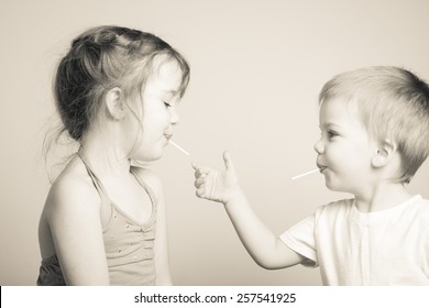 Black And White Photo Of Siblings Playing With Each Other's Lollipops