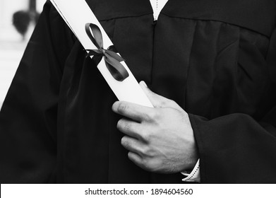 Black And White Photo Of  Student Holding Diploma On Graduation Day