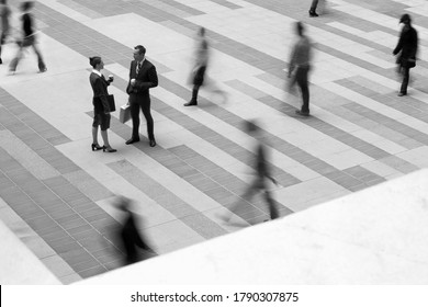 Black and White photo of two business people talking in blurred crowd