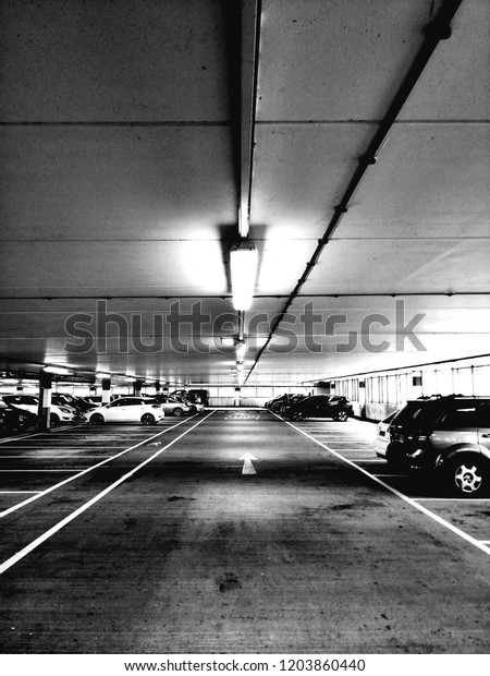 Black and white photo of urban underground car\
parking lot.