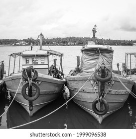 Black And White Photo Of Vintage Fishing Boats Parked With Tied Ropes