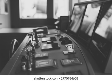 Black and white photo of wheelhouse, bridge of a modern newbuild superyacht, with wooden wheel, throttle controls, radar, auto-pilot, navigation and other control panels