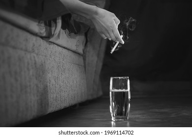 Black White Photo. A Woman's Hand Holding A Smoking Cigarette, There Is A Glass Of Alcohol Next To It. Smoking Is Dangerous For Women's Health. Cigarette Smoke.