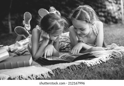 Black And White Photo Of Young Girls Looking At Family Photo Album