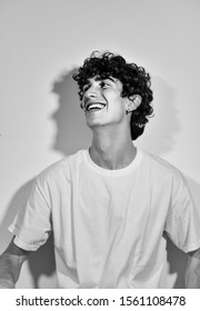 Black And White Photography. Portrait Of Young Handsome Italian Model Boy With Dark Curly Hair Posing For A Fashion Shooting On White Background