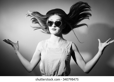 Black and white photography of surprised excited girl with hair blown away and glasses in the shape of hearts