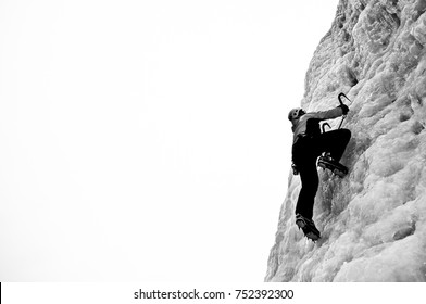 Black And White Pictue Of An Ice Climber Climbing Steep Ice Wall. Extreme Sport And Adventure.