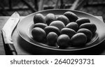 Black and White picture of a dish full Bengal Lemons, one Egg and a Kukri knife by the side. 