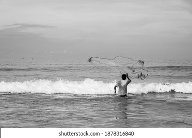 Black And White Picture Of Fisherman Cast A Net On Beach.