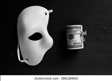 A Black And White Picture Of Masquerade And Fake Money. Scammer Concept.