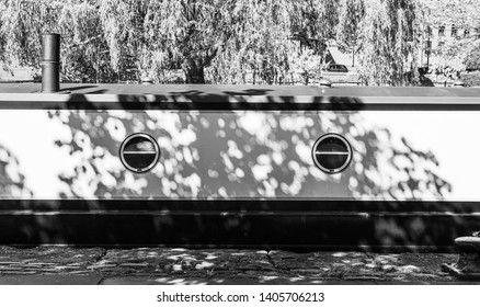 Black and white picture of the side of a boat under the light and shadow of the tree. Background image with abstract decoration.