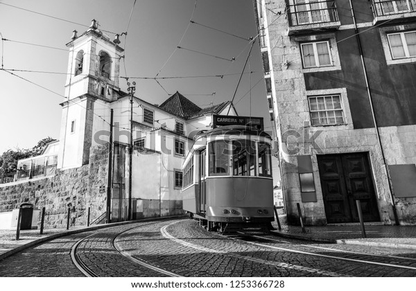 Black and white picture\
of a tram on the streets of Lisbon, Alfama, Portugal near Santa\
Luzia church