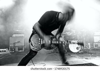 Black and white picture of a wild rock guitarist playing on stage. Blurred motion bright background. - Shutterstock ID 1748920175