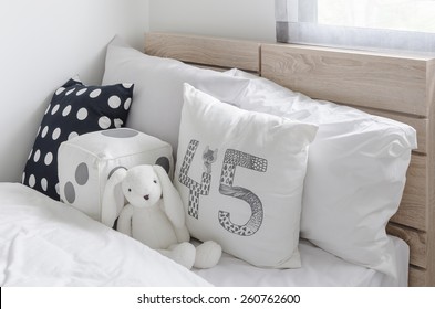 Black And White Pillows With Doll On Wooden Bed In Kid's Bedroom At Home