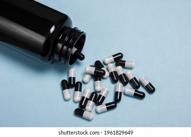 Black and white pills vitamins on a blue background and a jar. Protection against covid viruses, strengthening immunity, fighting and health.