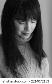 Black And White Portrait Of A 30 Year Old Caucasian Woman Wearing A Knitted Sweater. She Has Dark Hair And Is Looking Downwards. Her Eyes Are Closed.