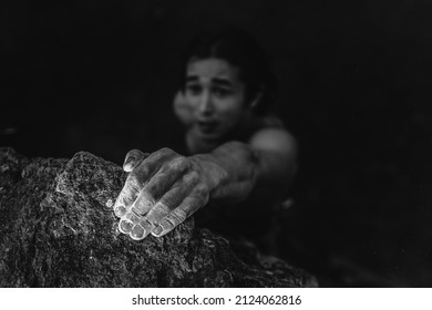Black And White Portrait Of An Asian Man Who Is Engaged In Rock Climbing. Climber Holding On To A Rock With One Hand. Climber's Hands In White Powder Of Magnesia.