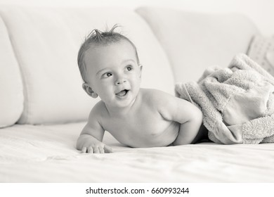 Black And White Portrait Of Baby Boy Lying Under Blanket On Sofa