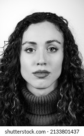 Black And White Portrait Of A Beautiful Brunette Girl With Long Curly Hair And Hazel Eyes And Square Jaw And Chin. Perfect Skin, Looking At The Camera.