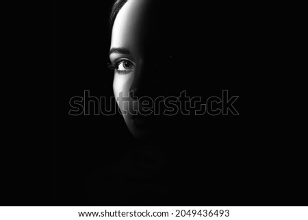 black and white portrait of beautiful girl eye. pretty young woman face part in dark