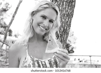 Black And White Portrait Of Beautiful Mature Woman On Beach Summer Holiday, Joyfully Smiling Looking Holding Eating Watermelon, Outdoors. Healthy Eating, Wellness Fruit Food, Leisure Lifestyle.