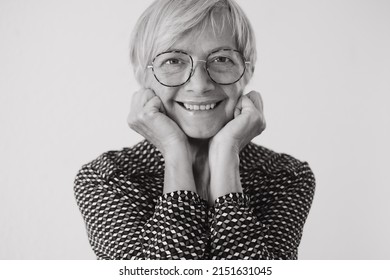 Black And White Portrait Of Beautiful Older Woman Wearing Glasses Looking At Camera Smiling. Short Haired Caucasian Lady Feeling In A Good Mood