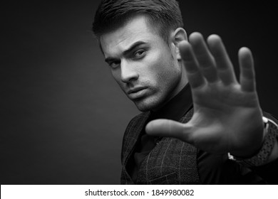 Black And White Portrait Of Beautyful Guy On Dark Background. High Fashion Model Posing In Studio. Attractive Man In Classic Suit.
