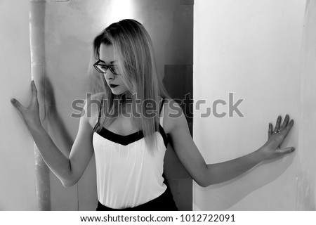Black and white portrait of blond girl in hipster glasses, Beautiful blonde with glasses on a light background, black and white photo