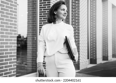 Black And White Portrait Of Confident Middle Aged Businesswoman Walking On The Street Looking Away 