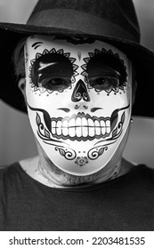 Black And White Portrait Of An Elderly Lady With A Catrina Mask And Hat, Celebrating Halloween And All Souls' Day, On A White Background. Celebration, Costume, Party And Mask Concept.