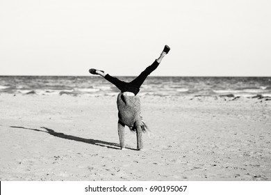 Black and white portrait of funny white Caucasian child kid teenager doing cartwheel playing on beach on sunset. Happy lifestyle childhood concept