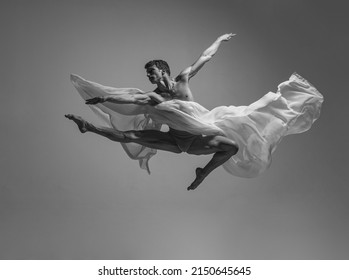 Black and white portrait of graceful muscled male ballet dancer dancing with fabric, cloth isolated on grey studio background. Grace, art, beauty, contemp dance concept. Weightless, flexible actor - Powered by Shutterstock