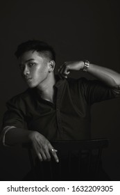 Black and White portrait of handsome Asian male model with beautiful eyes in the dark black background.